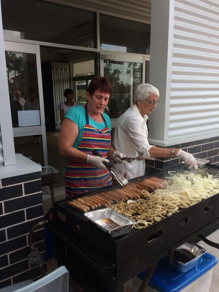 Volunteers cooking sausages and onions at a community barbecue