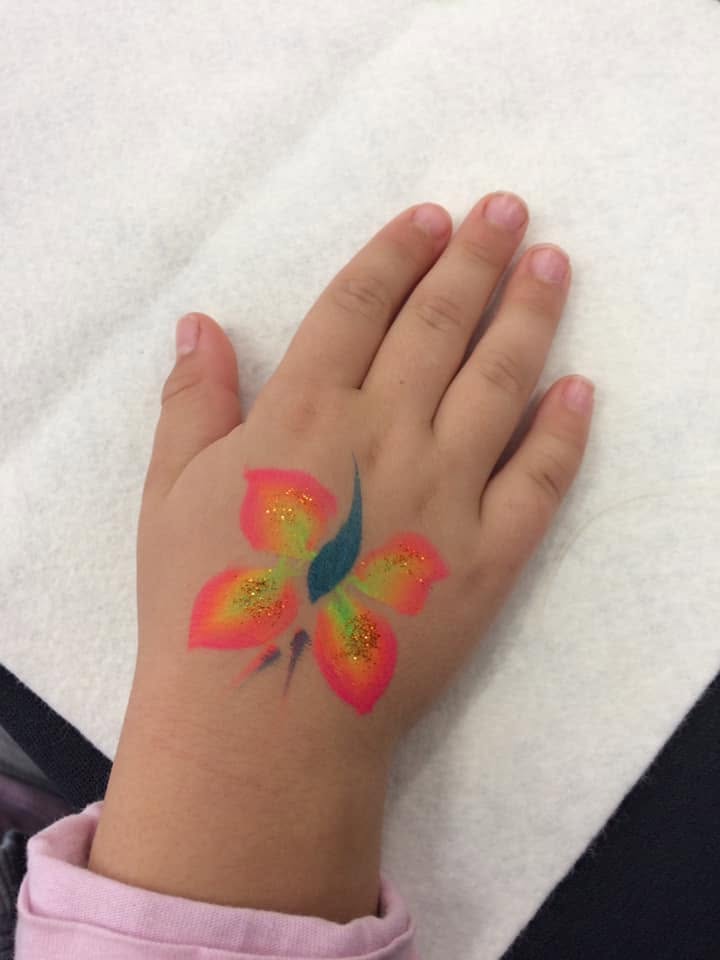 Colourful butterfly design painted on a child’s hand